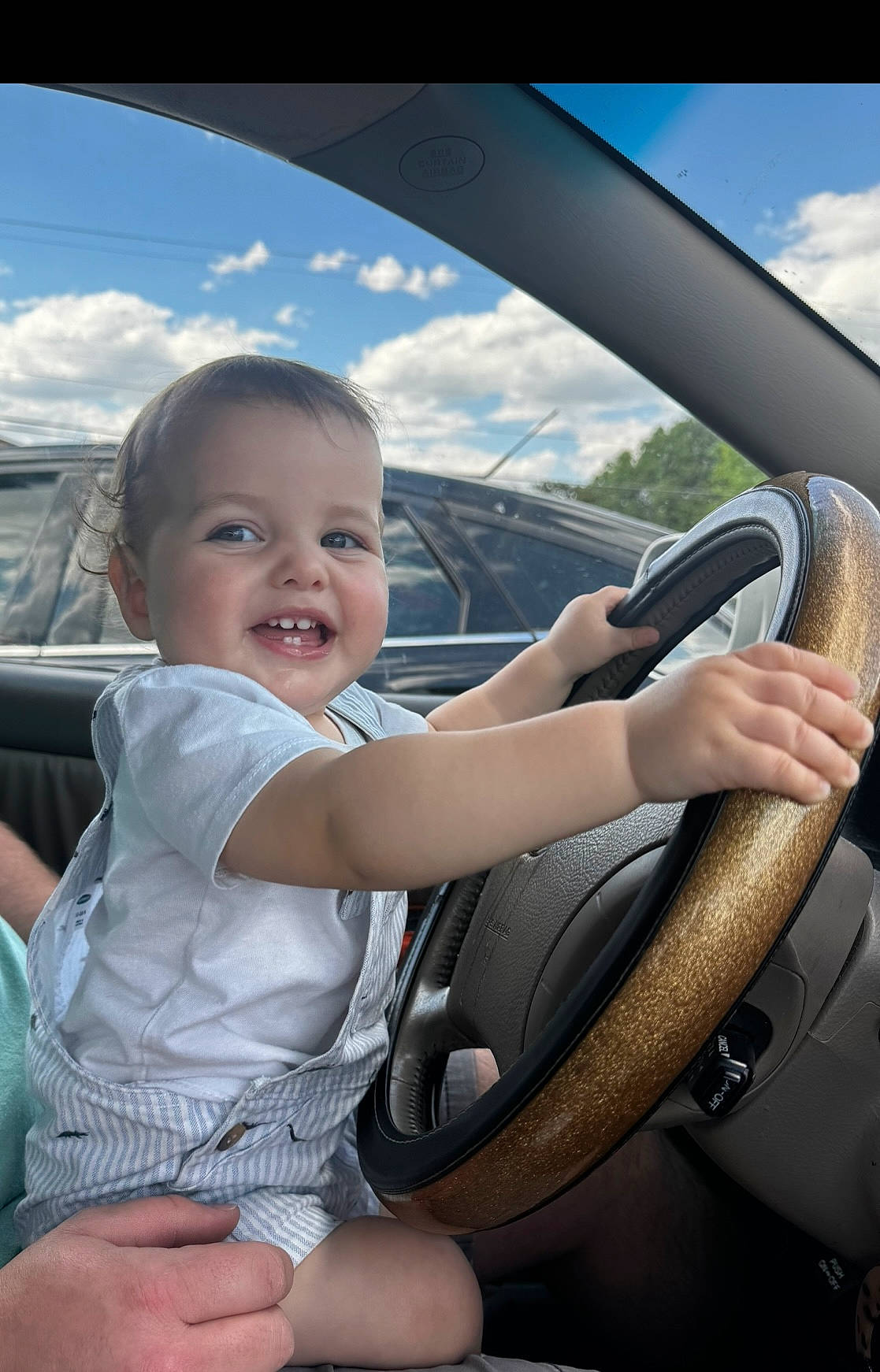 Remington is registered to the contest to win money with this photo: auto_part, automotive_design, automotive_exterior, automotive_mirror, cloud, finger, flash_photography, hand, happy, joy, leisure, mode_of_transport, motor_vehicle, person, personal_luxury_car, sky, smile, steering_part, steering_wheel, toddler