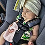 baby, sleeping, car_seat, hat, blanket, child, infant, safety_harness, clothing, seatbelt, warning_label, peaceful, cute, indoor, resting, child_safety, soft_texture, pale_skin, toddler, nap