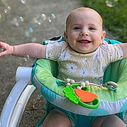 Sophia is registered to the contest to win money with this photo: baby, walker, bubbles, outdoor, grass, smile, happy, child, toy, green, white, clothing, shorts, arms, seat, head, face, skin, playful, sunlight
