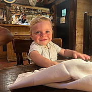 Lucas a rejoint le concours — aidez-le/la à gagner de superbes lots ! toddler, child, smile, face, wooden_table, napkin, restaurant, interior, wooden_chair, deer_head, portrait, happy, blond_hair, indoor, person, rustic, warm_lighting, bar, glassware, background