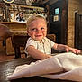 toddler, child, smile, face, wooden_table, napkin, restaurant, interior, wooden_chair, deer_head, portrait, happy, blond_hair, indoor, person, rustic, warm_lighting, bar, glassware, background