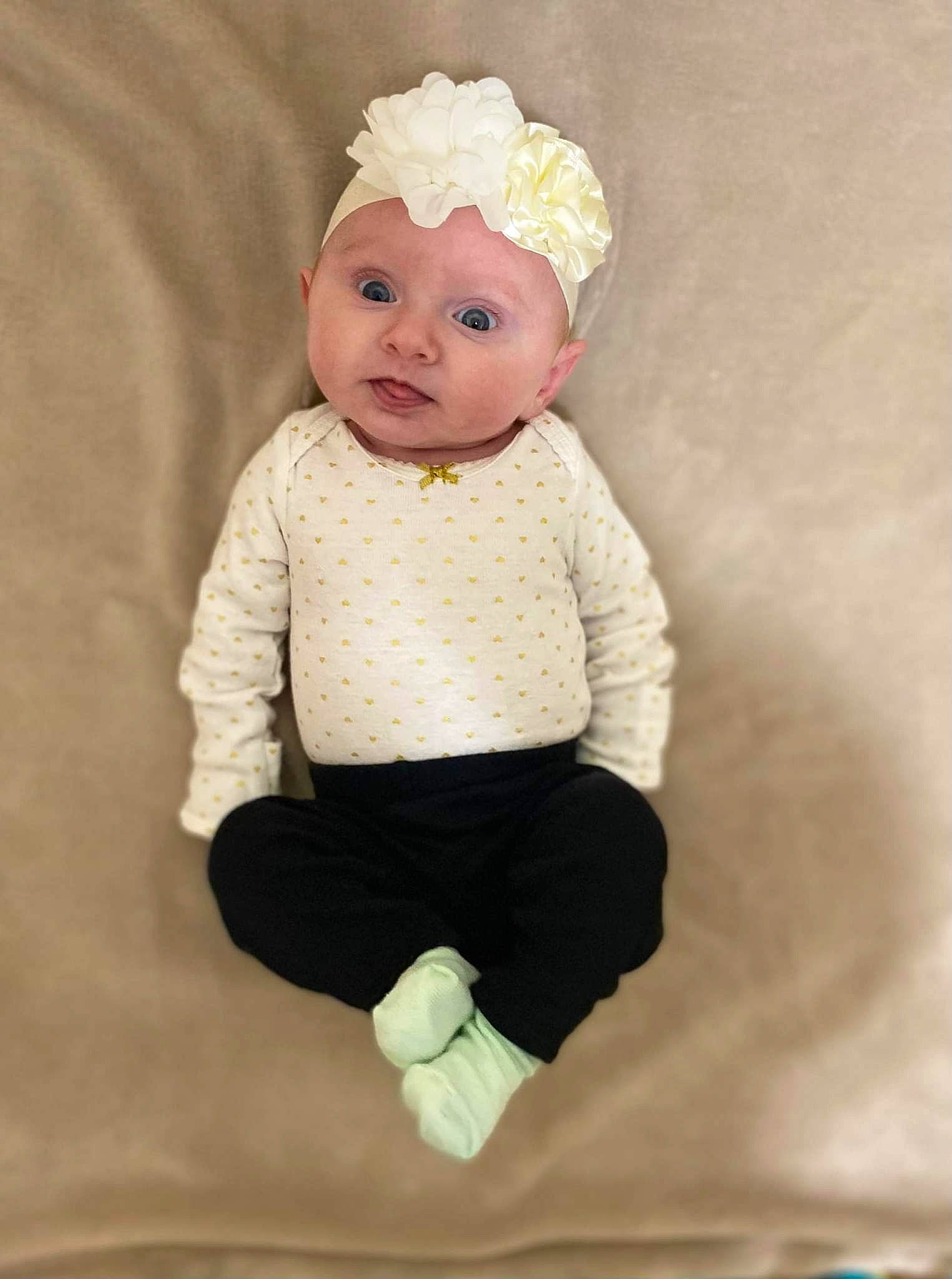 Liliana is registered to the contest to win money with this photo: arm, baby, baby_toddler_clothing, cheek, child, chin, embellishment, fashion_accessory, head, headgear, headpiece, headwear, human_body, knee, outerwear, pattern, peach, person, sitting, sleeve