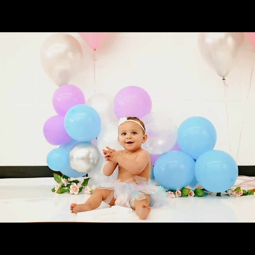 Zelda joined the competition — help win amazing prizes! baby, balloon, clothing, dress, face, flower, flowerarrangement, flowerbouquet, happy, hat, head, indoors, people, person, photography, plant, portrait, purple, smile, sphere