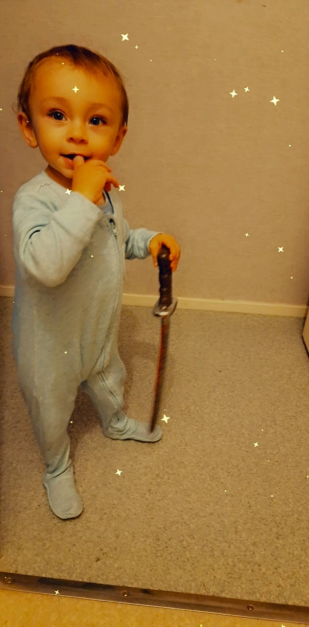 Nino participe au concours pour gagner de l'argent avec cette photo : baby, baby_toddler_clothing, cheek, child, dress_shirt, finger, floor, flooring, gesture, human_body, human_leg, knee, person, room, skin, sleeve, standing, suit, thumb, toddler