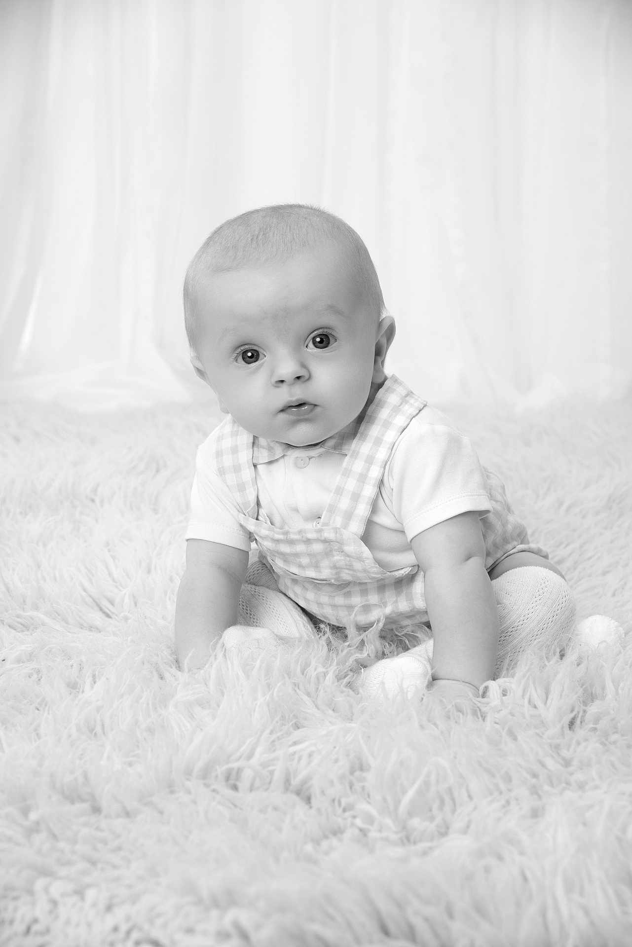 James joined the competition — help win amazing prizes! baby, child, infant, portrait, black_and_white, curtains, fluffy_rug, sitting, cute, wide_eyes, overall, knitted_tights, soft_lighting, indoor, young_child, monochrome, studio_photo, curiosity, expression, pose