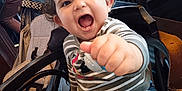 Diego participe au concours pour gagner de l'argent avec cette photo : child, clothing, curly_hair, expression, face, hand, happy, high_chair, indoor, pants, person, reaching_out, seated, shoes, smiling, striped_shirt, stroller, toddler, toy, wooden_railings