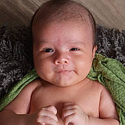 Julian is registered to the contest to win money with this photo: baby, infant, child, face, smile, hands, skin, towel, texture, blanket, portrait, cute, lying_down, indoors, young, newborn, expression, human, closeup, soft