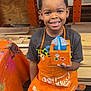 Christopher joined the competition — help win amazing prizes! child, smiling, boy, apron, craft, workshop, wood, paint, table, project, indoor, person, clothing, hands, face, floor, shoes, woodworking, colorful, happy