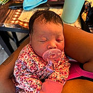 My Ari joined the competition — help win amazing prizes! arms, baby, closeup, clothing, cute, floral_outfit, hand, household_items, indoor, infant, newborn, pacifier, peaceful, person, pink, portrait, resting, skin, sleeping, table