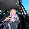 woman, dog, pet, car_interior, glasses, pink_bow, pink_dyed_fur, seat, window, blue_sky, casual_clothing, affection, portrait, selfie, daylight, cute, fluffy, leisure, hand, love