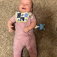 Hazel joined the competition — help win amazing prizes! baby, infant, carpet, pink_onesie, bib, smiling, happy, footwear, indoor, toy, child, person, skin, face, head, clothing, caucasian, baby_shoes, lying_down, playful