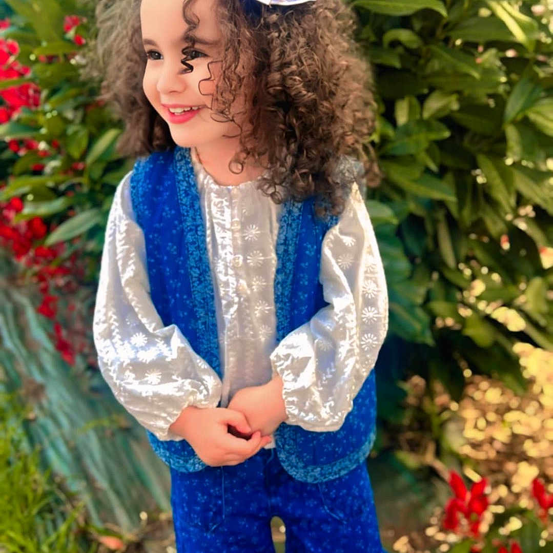 Janet participe au concours pour gagner de l'argent avec cette photo : blue_pants, blue_vest, bow, child, curly_hair, cute, fashion, flowers, grass, greenery, happy, nature, outdoor, person, playful, portrait, smile, standing, sunlight, white_blouse