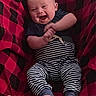 baby, blanket, cozy, fabric, face, feet, hands, happy, head, indoor, infant, laughing, onesie, pattern, person, plaid_blanket, portrait, smiling, striped_pants, toes