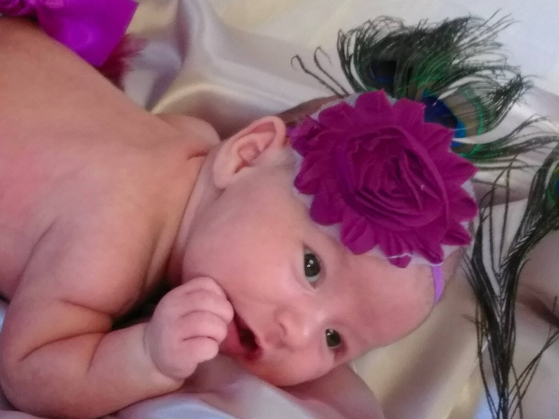 Amy is registered to the contest to win money with this photo: cheek, child, face, finger, forehead, girl, hair_accessory, head, headband, headgear, headpiece, infant, person, petal, pink, product, skin, toddler