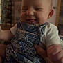Zara joined the competition — help win amazing prizes! baby, child, infant, smile, clothing, overalls, hand, indoor, person, face, cute, young, happy, skin, head, arm, furniture, blur, background, portrait