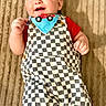 Kasin is registered to the contest to win money with this photo: baby, child, infant, smiling, happy, portrait, lying_down, carpet, checkered_outfit, bib, toy_car, red_shirt, barefoot, indoor, home, floor, wall_decor, fist, looking_at_camera, colorful