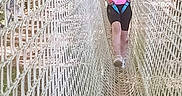 Mia a rejoint le concours — aidez-le/la à gagner de superbes lots ! child, rope_bridge, netting, safety_harness, pink_clothing, outdoor, playground, smiling, walking, young_girl, adventure, net, daylight, activity, nature, fun, person, shoes, rope, recreation