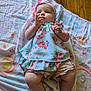 baby, infant, child, blanket, floor, wooden_floor, headband, bow, dress, floral_pattern, legs, hands, skin, cute, indoors, laying_down, person, apparel, soft_texture, natural_light