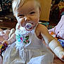 Abby joined the competition — help win amazing prizes! baby, child, pacifier, white_dress, embroidery, smiling, indoor, toys, blanket, candid, face, person, cute, sitting, playful, hair, expression, infant, home, childhood