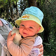 Félix a rejoint le concours — aidez-le/la à gagner de superbes lots ! baby, child, hat, toy, forest, nature, outdoors, person, hugging, sunlight, trees, greenery, cute, infant, holding, smiling, clothing, adult, daylight, face
