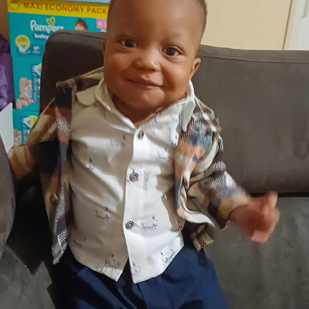 Tidi a rejoint le concours — aidez-le/la à gagner de superbes lots ! baby, child, clothing, couch, cute, face, furniture, happy, home, indoor, jacket, person, portrait, shirt, shoes, shorts, sitting, smile, toddler, young_child