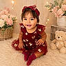 toddler, child, dress, headband, maroon, golden_bows, smiling, sitting, carpet, fluffy, teddy_bear, flowers, basket, indoor, cute, portrait, happy, baby, soft_lighting, decor