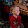 child, toddler, red_sweater, mickey_mouse, chair, indoor, holiday_bags, yellow_armchair, carpet, smile, blond_hair, casual_clothing, sneakers, floor, portrait, seated, furniture, home, festive, young_child