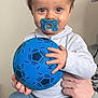 Solann a rejoint le concours — aidez-le/la à gagner de superbes lots ! child, toddler, pacifier, blue_ball, indoor, person, sitting, clothing, pants, sweater, hand, face, eyes, hair, toy, adult_hand, comfort, baby, casual, portrait
