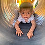 child, crawling, curious, daylight, exploration, eyes, face, fun, hands, metal, outdoor, person, play_structure, playground, short_hair, toddler, tunnel, white_shirt, yellow, young