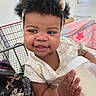 baby, bag, child, closeup, clothing, curly_hair, cute, hand, happy, headband, holding, indoor, infant, milk_bottle, person, pink_blanket, portrait, shopping_cart, skin, smiling