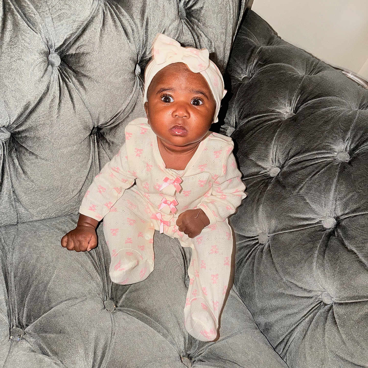 Romani joined the competition — help win amazing prizes! baby, infant, child, portrait, sitting, sofa, couch, tufted_furniture, gray, headband, bow, pink, onesie, baby_clothing, wide_eyed, looking_at_camera, indoor, home, photography, adorable