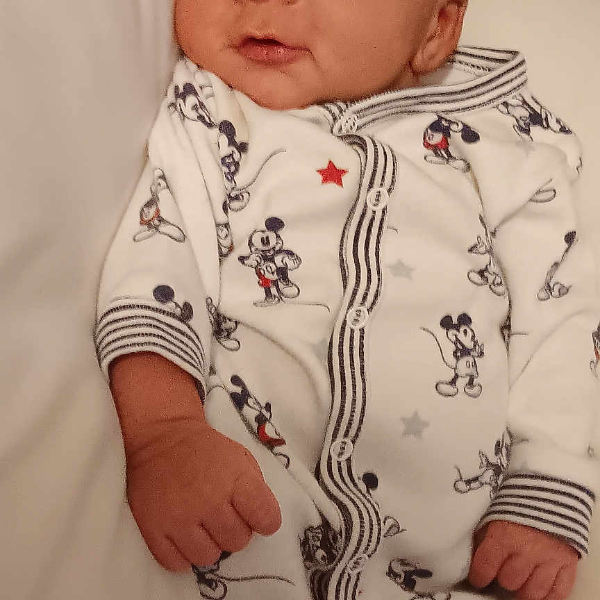 Waylan joined the competition — help win amazing prizes! baby, infant, child, portrait, bed, bedding, onesie, clothing, mickey_mouse, cartoon, sleeping, lying_down, face, hands, eyes, serious_expression, indoor, home, soft_lighting, candid