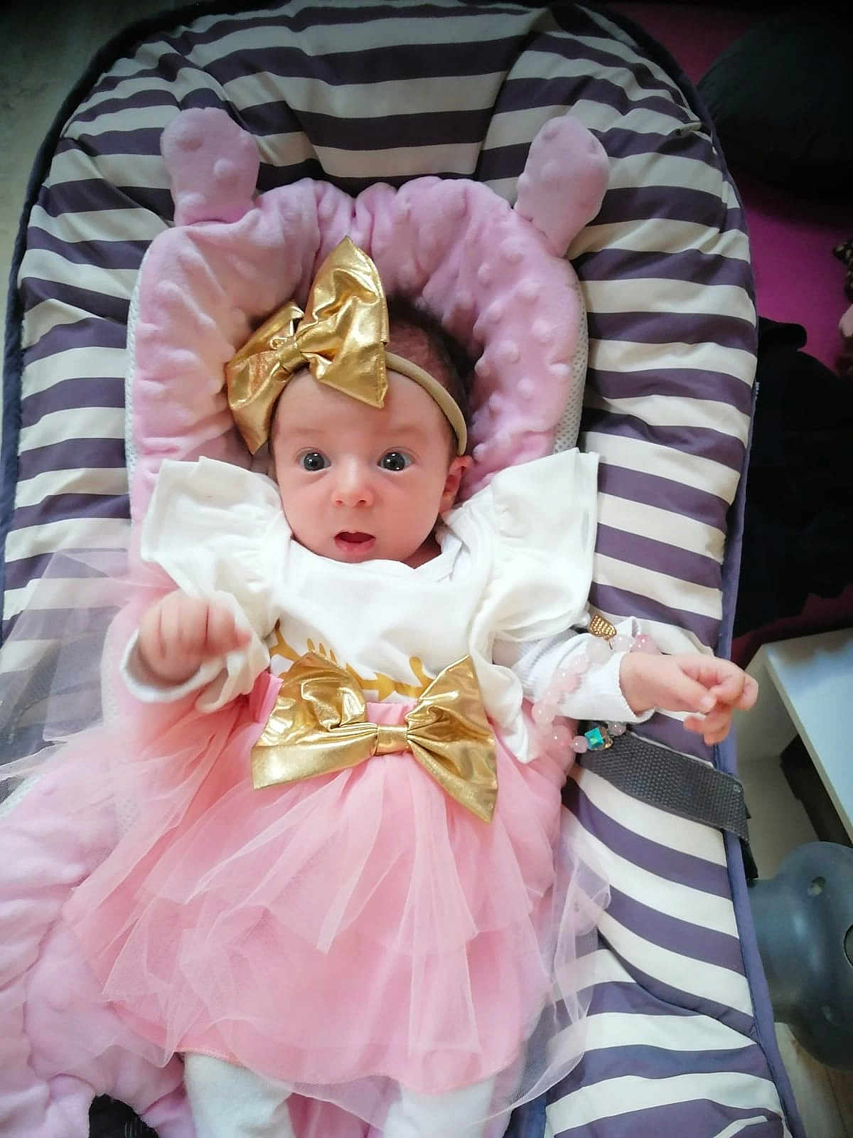 Chloe a rejoint le concours — aidez-le/la à gagner de superbes lots ! baby, infant, tutu, pink, gold_bow, headband, striped, cushion, seat, clothing, cute, wide_eyes, portrait, indoors, child, toddler, fabric, soft, bracelet, expression