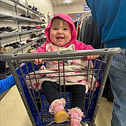 Lilliana joined the competition — help win amazing prizes! baby, child, shopping_cart, smiling, hoodie, pink, shoes, store, aisle, floor, person, clothing, jeans, hand, metal, baby_shoes, blanket, happy, indoor, retail