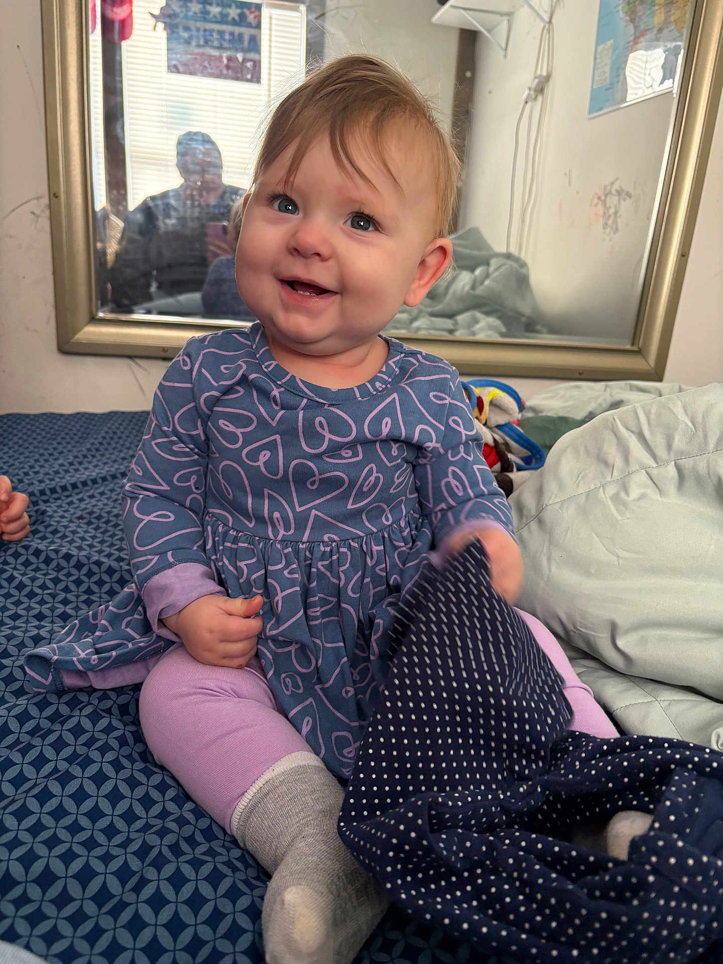 Lilliana joined the competition — help win amazing prizes! baby, child, smiling, sitting, bed, blanket, mirror, reflection, clothing, dress, leggings, sock, pattern, indoor, person, cute, happy, home, toy, fabric