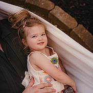 Eleanor is registered to the contest to win money with this photo: child, girl, hammock, outdoor, relaxing, smiling, hair_clip, hand, watch, arm, casual_clothing, nature, garden, portrait, cute, comfort, family, toddler, person, summer
