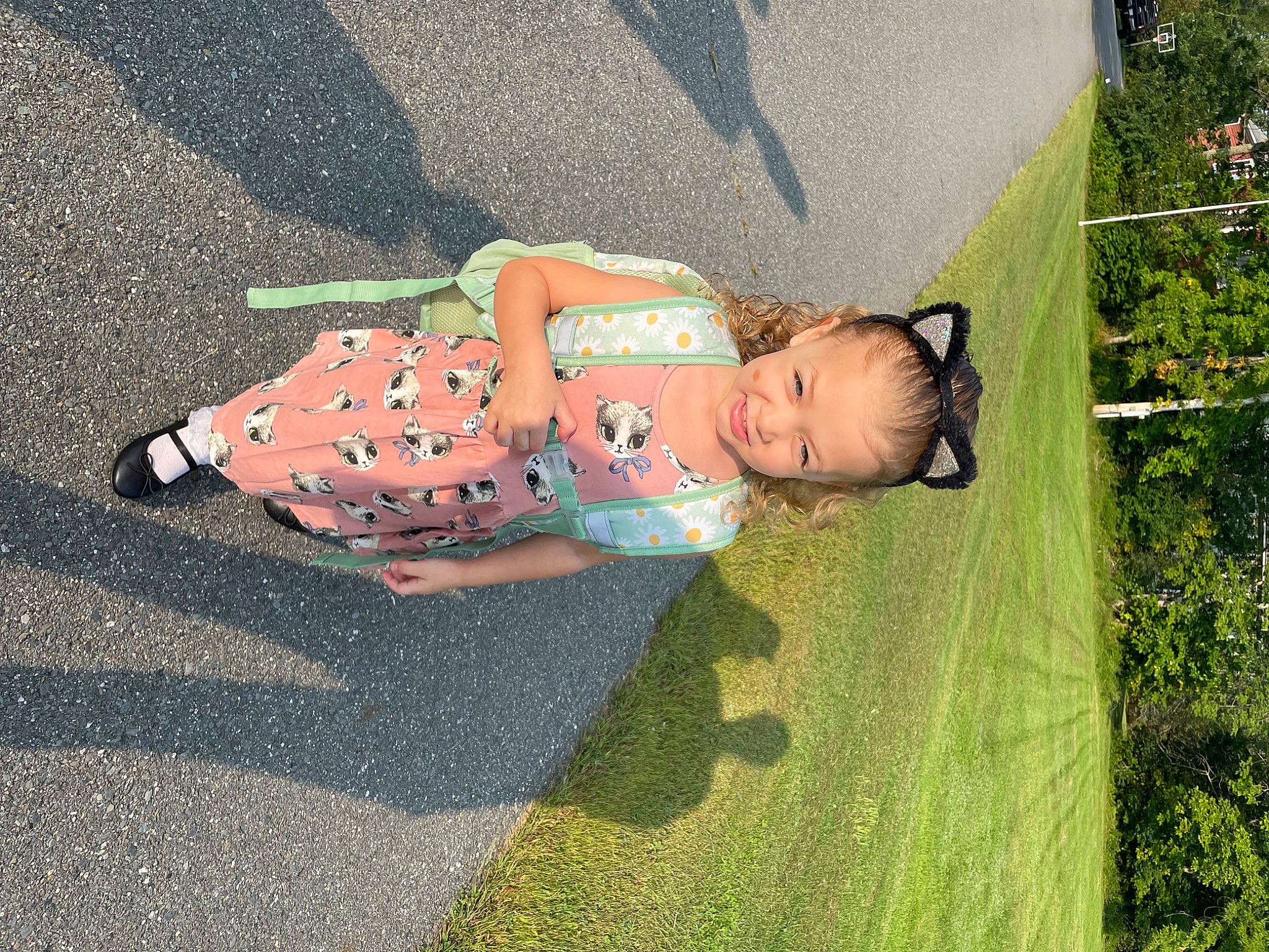 Katherine is registered to the contest to win money with this photo: asphalt, baby, baby_products, baby_toddler_clothing, child, dress, fun, grass, human_leg, joy, landscape, leisure, pattern, people_in_nature, person, plant, road_surface, shadow, sidewalk, sitting