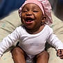 baby, smiling, pink_bonnet, white_onesie, cushion, sitting, happy, infant, child, cute, sock, baby_sock, indoor, portrait, face, headwear, apparel, comfort, joy, young_child