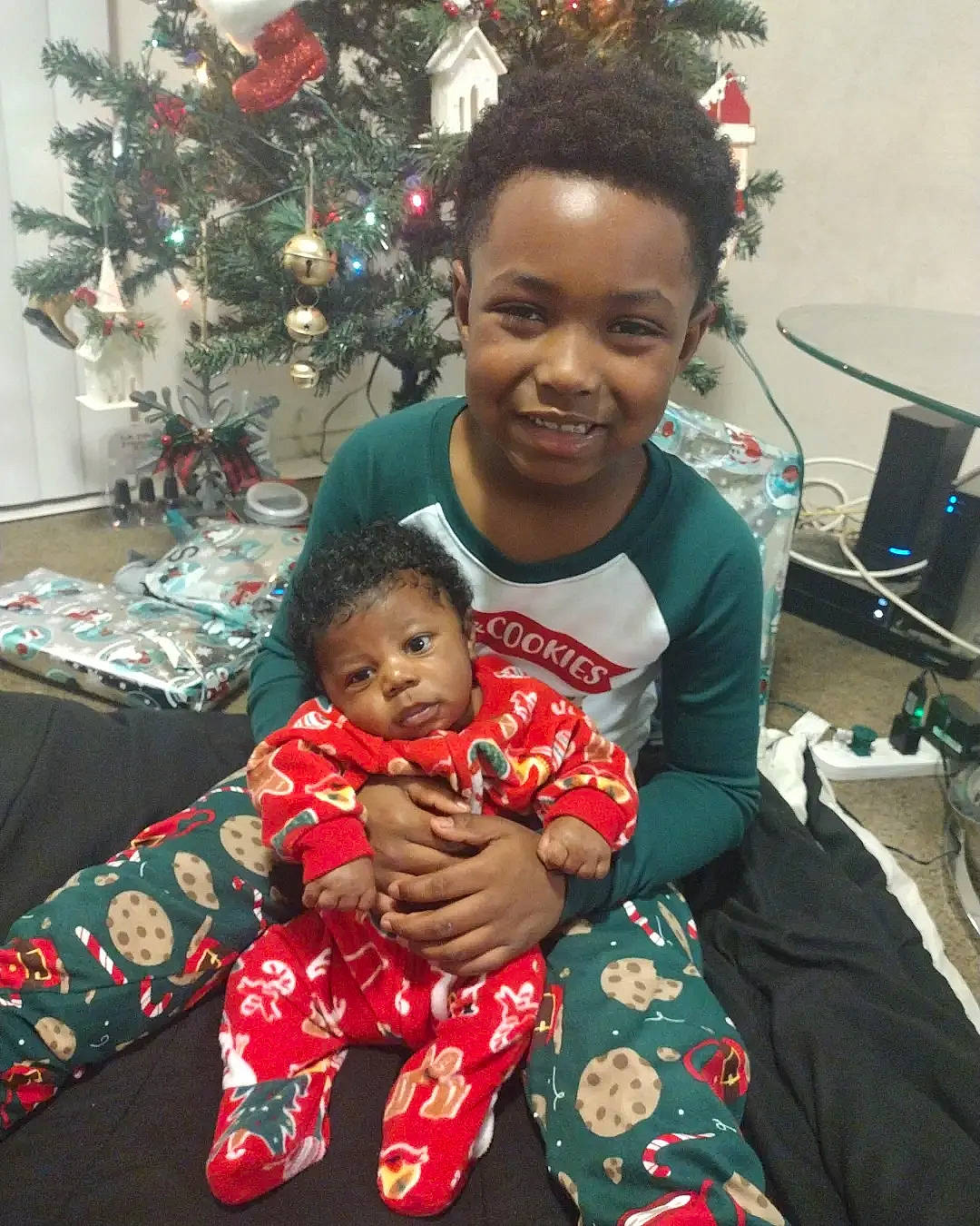 Nolan is registered to the contest to win money with this photo: baby, chair, christmas, christmas_decoration, christmas_ornament, christmas_tree, computer_keyboard, computer_monitor, event, fun, happy, holiday, holiday_ornament, joy, ornament, person, plant, smile, snapshot, standing