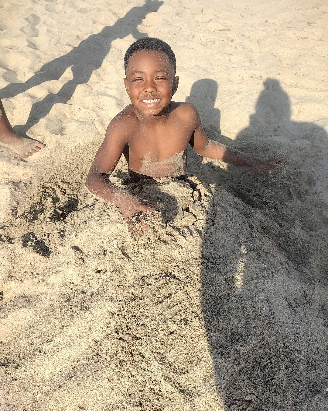 Nolan is registered to the contest to win money with this photo: barechested, beach, chest, child, face, flash_photography, fun, happy, joy, landscape, leisure, ocean, people_in_nature, people_on_beach, person, play, rock, sand, sitting, smile