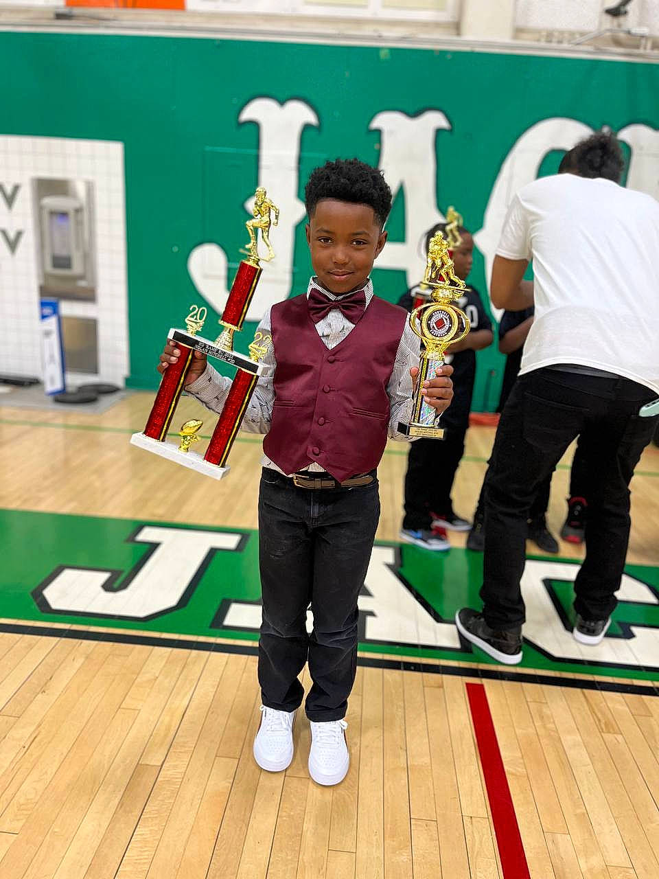 Nolan is registered to the contest to win money with this photo: child, competition, competition_event, event, flooring, fun, green, hardwood, joy, leisure, person, room, sports, sportswear, standing, sweatpant, t_shirt, uniform, visual_arts, wood
