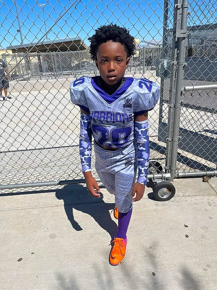 Nolan is registered to the contest to win money with this photo: baseball_uniform, chain_link_fencing, competition_event, denim, electric_blue, fence, fun, jersey, leisure, mesh, person, player, sky, sports, sports_uniform, sportswear, t_shirt, team_sport, toddler, uniform