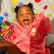 Alexia is registered to the contest to win money with this photo: child, toddler, smiling, pink_robe, toy, colorful, balloons, stars, happy, indoor, cute, face, person, playful, fun, cozy, curly_hair, expression, background, soft