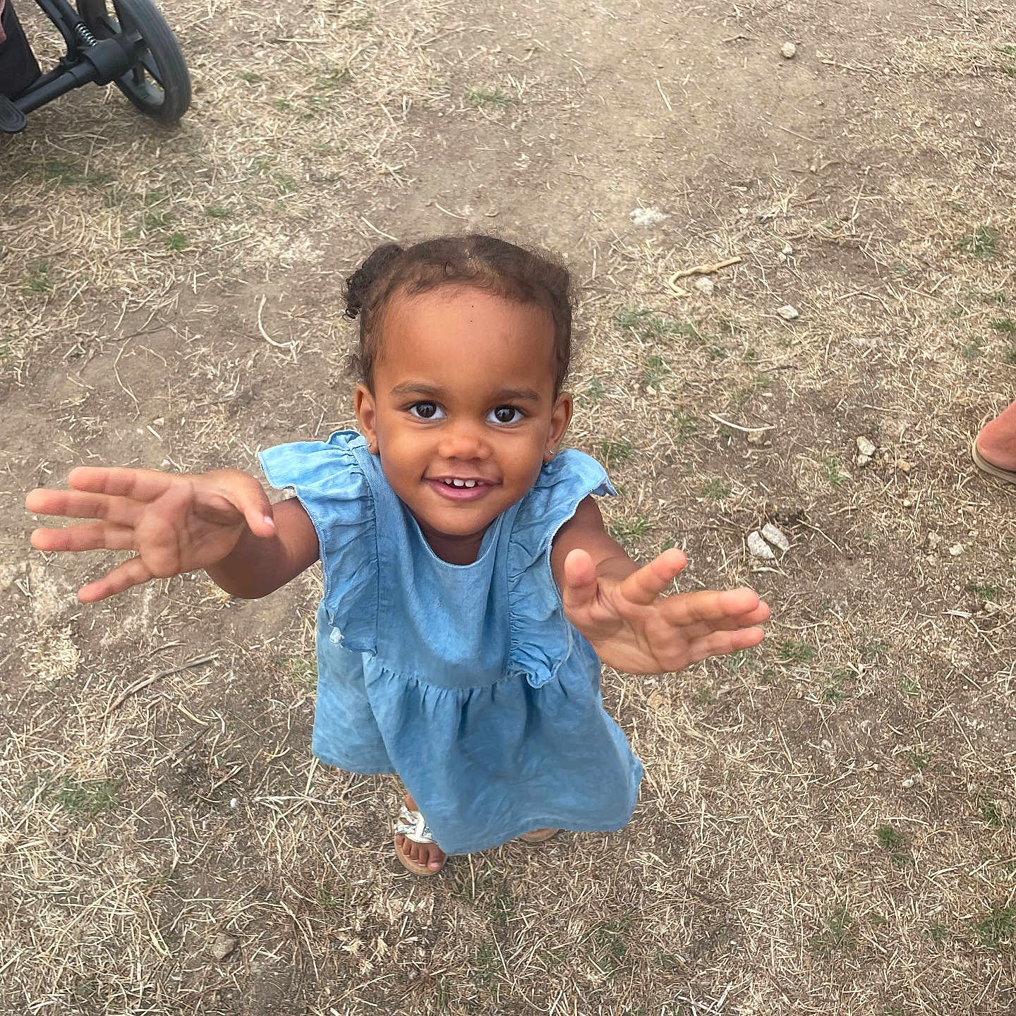 Seyana participe au concours pour gagner de l'argent avec cette photo : barefoot, blue_dress, casual, child, cute, daylight, dirt, grass, happy, nature, outdoor, person, playful, portrait, reaching, smiling, stroller_wheel, summer, toddler, young_child