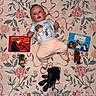 Emma joined the competition — help win amazing prizes! baby, child, carpet, floral_pattern, star_wars, toy, book, onesie, cute, indoor, person, face, plush_toy, lying_down, rosy_cheeks, pink_pants, decorative, patterned, small_child, curious