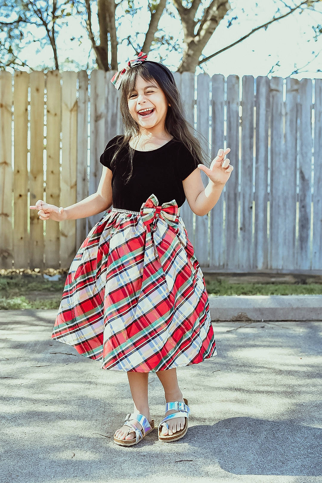 Arielle is registered to the contest to win money with this photo: day_dress, dress, face, fence, footwear, hairstyle, hand, happy, joy, knee, leg, person, plaid, shoe, sleeve, smile, street_fashion, tartan, textile, thigh