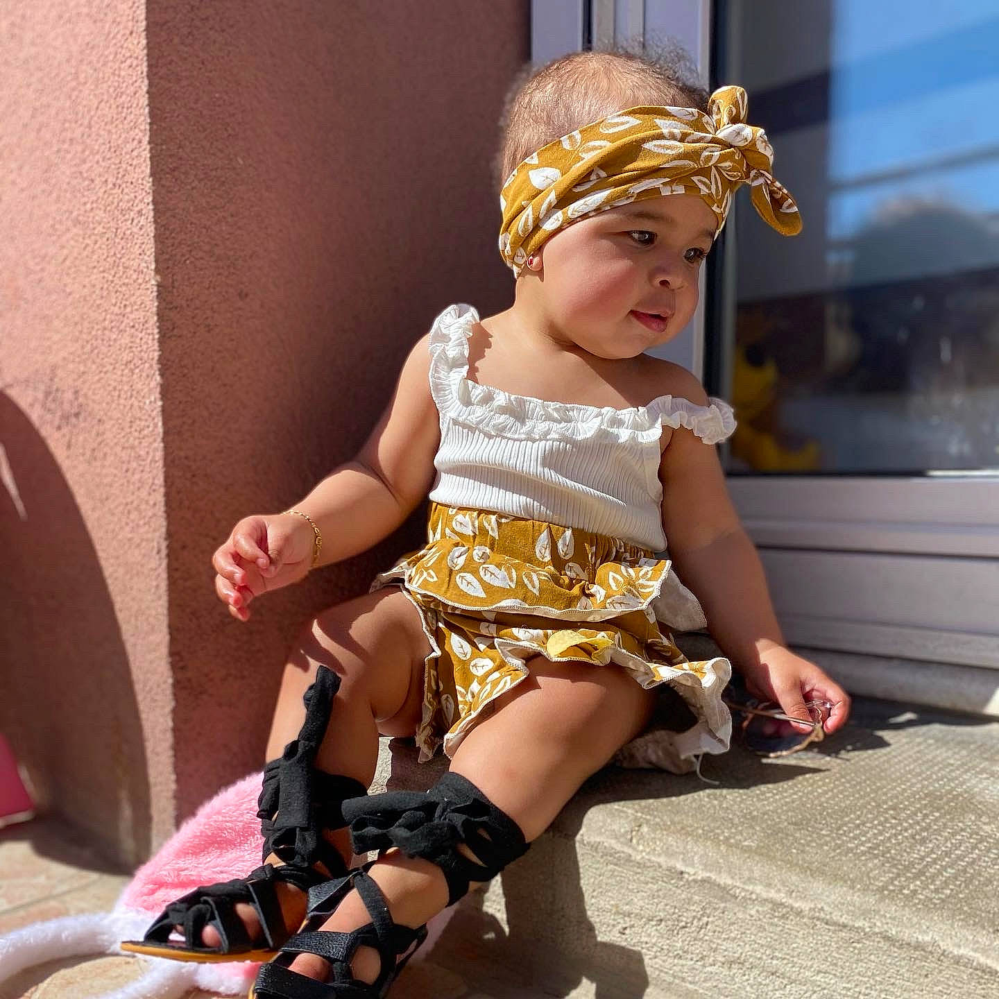 Jahyana participe au concours pour gagner de l'argent avec cette photo : baby_toddler_clothing, blond, child, fashion_accessory, fashion_design, foot, fun, happy, headband, headpiece, headwear, human_leg, jewellery, knee, pattern, person, pink, sandal, sitting, sock