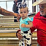 Brooklynn joined the competition — help win amazing prizes! toddler, child, cow_print, bow, pants, man, older_man, cowboy_hat, tattoo, hand_holding, bleachers, fence, camera, beard, red_jacket, light_blue_shirt, outdoor, person, photography, support