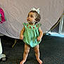 Brooklynn is registered to the contest to win money with this photo: toddler, child, baby, standing, barefoot, green_dress, bow, curly_hair, indoor, carpet, looking_up, cute, innocent, portrait, person, clothing, floor, expression, background, room