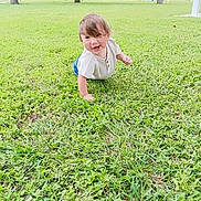 Jeremiah is registered to the contest to win money with this photo: toddler, child, grass, outdoor, park, trees, greenery, crawling, smiling, happy, casual_clothing, short_sleeves, nature, daylight, playful, young_child, lawn, residential_area, casual, portrait